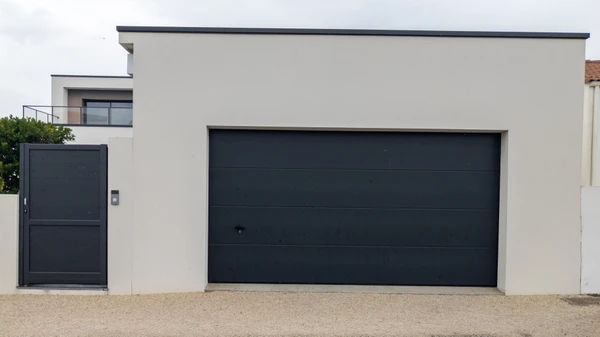 Fa&ccedil;ade ext&eacute;rieure de maison contemporaine avec porte de garage sectionnelle anthracite &agrave; panneaux horizontaux et portillon assorti