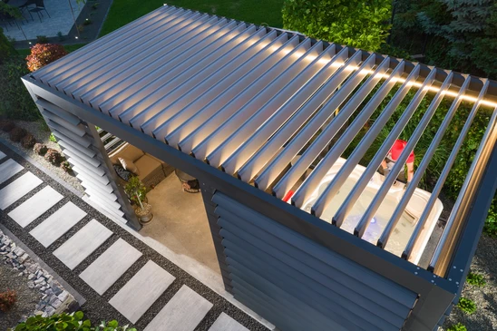 V&eacute;randa ferm&eacute;e avec grandes baies vitr&eacute;es coulissantes donnant sur jardin paysager et plan d'eau