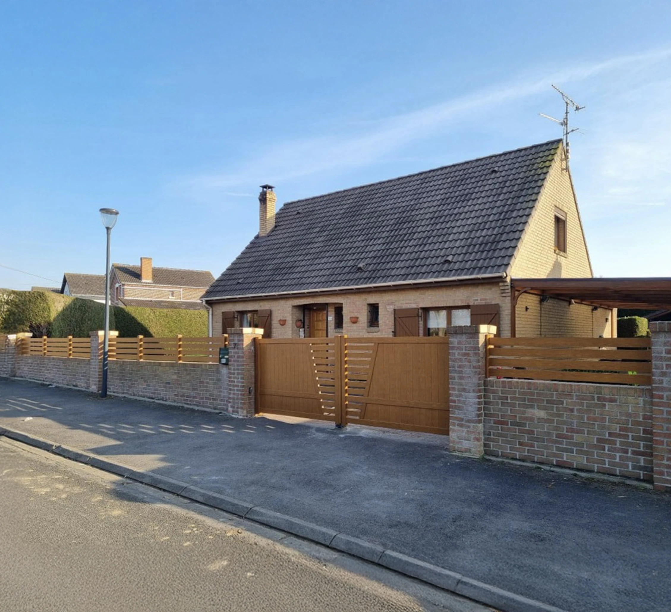 Entrée principale d'une maison contemporaine avec terrasse couverte et jardin paysager