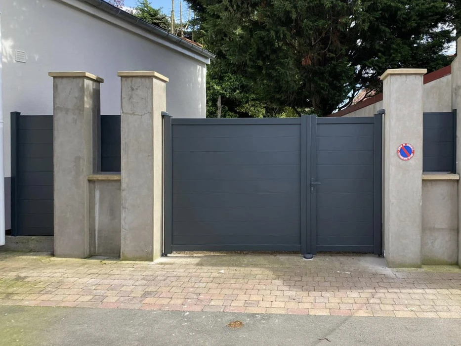 Partie d'une maison résidentielle blanche avec portes brunes, fenêtres et terrasse en matériaux composites gris foncé ou anthracite wpc avec balustrades en bois à l'extérieur