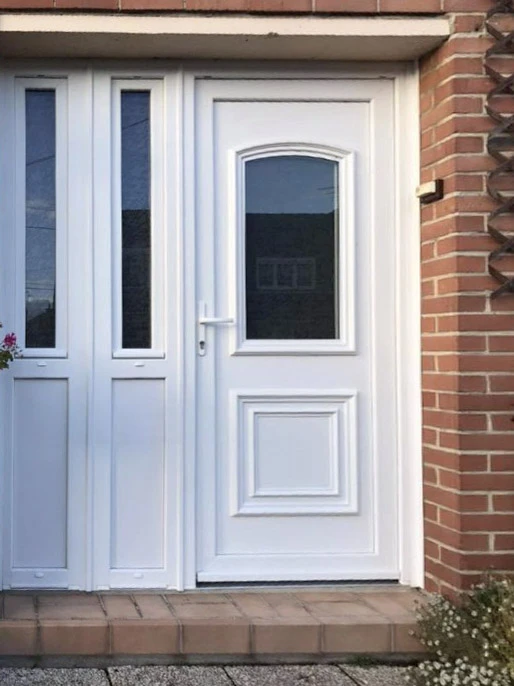 Partie d'une maison résidentielle blanche avec portes brunes, fenêtres et terrasse en matériaux composites gris foncé ou anthracite wpc avec balustrades en bois à l'extérieur