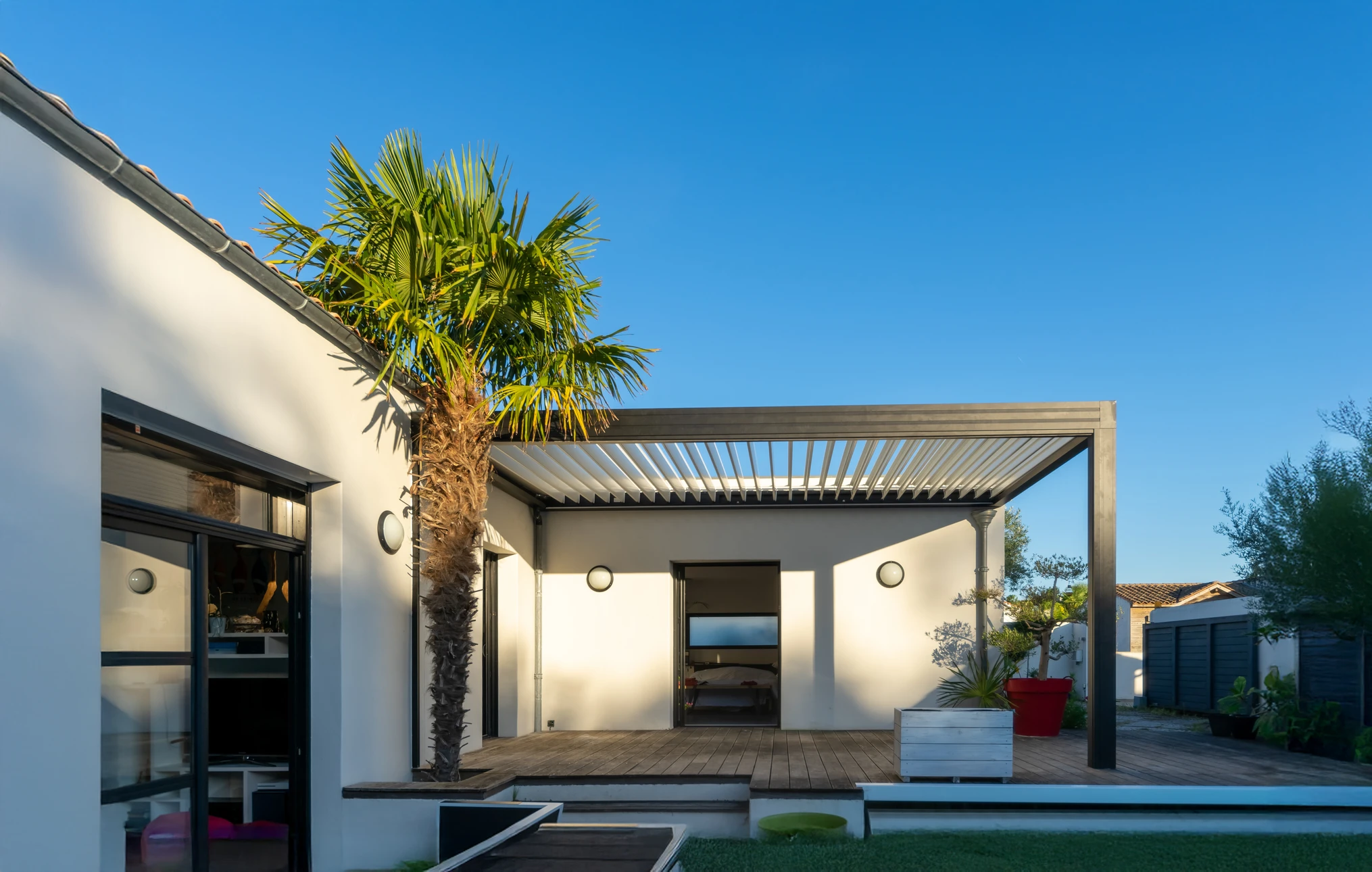 Extérieur résidentiel avec maison moderne dotée d'une véranda vitrée et mobilier de jardin en bois
