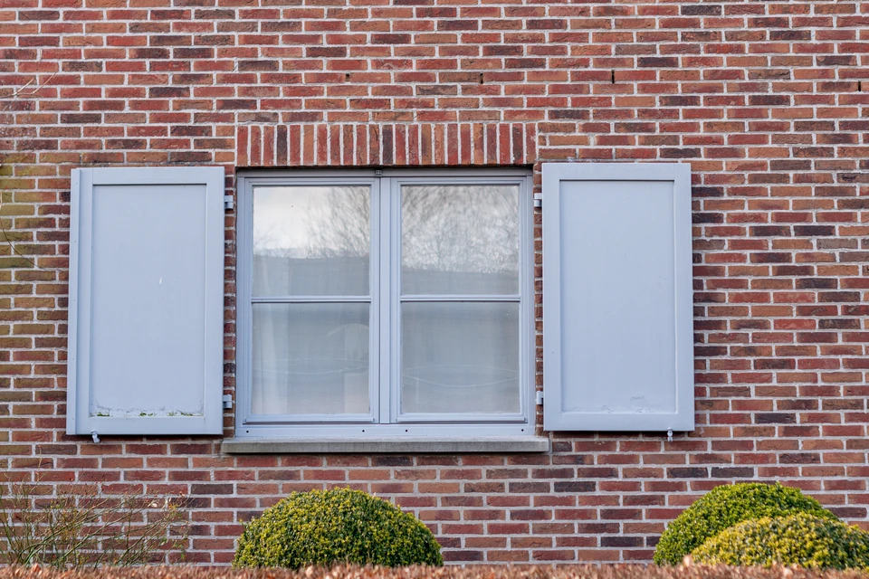 Deux ouvriers en tenue de protection travaillent sur une nacelle élévatrice à ciseaux jaune devant un bâtiment résidentiel blanc